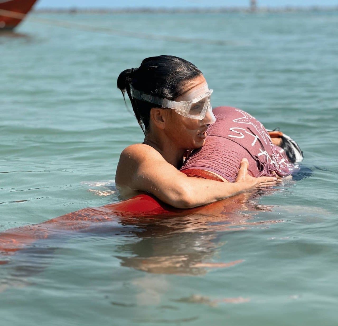 One person supporting another in shallow sea water.